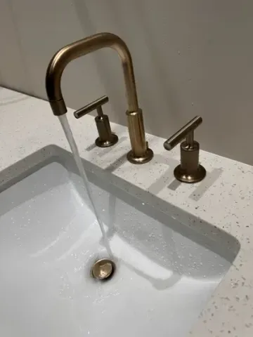 A bathroom sink with water running from the faucet.