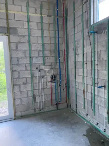 New construction plumbing rough-in with PEX supply lines running along concrete block walls