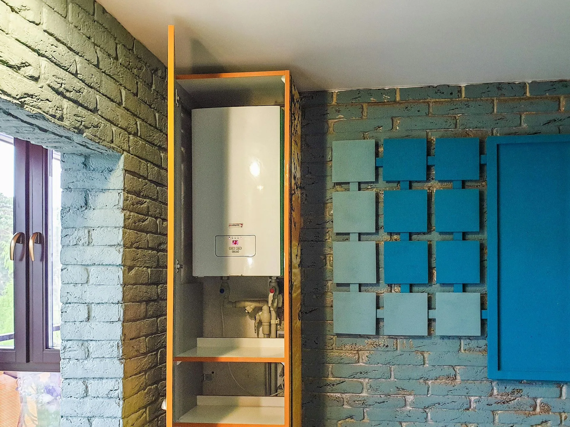 Small room with exposed brick walls, a wall-mounted heater, and blue square tiles on the right.