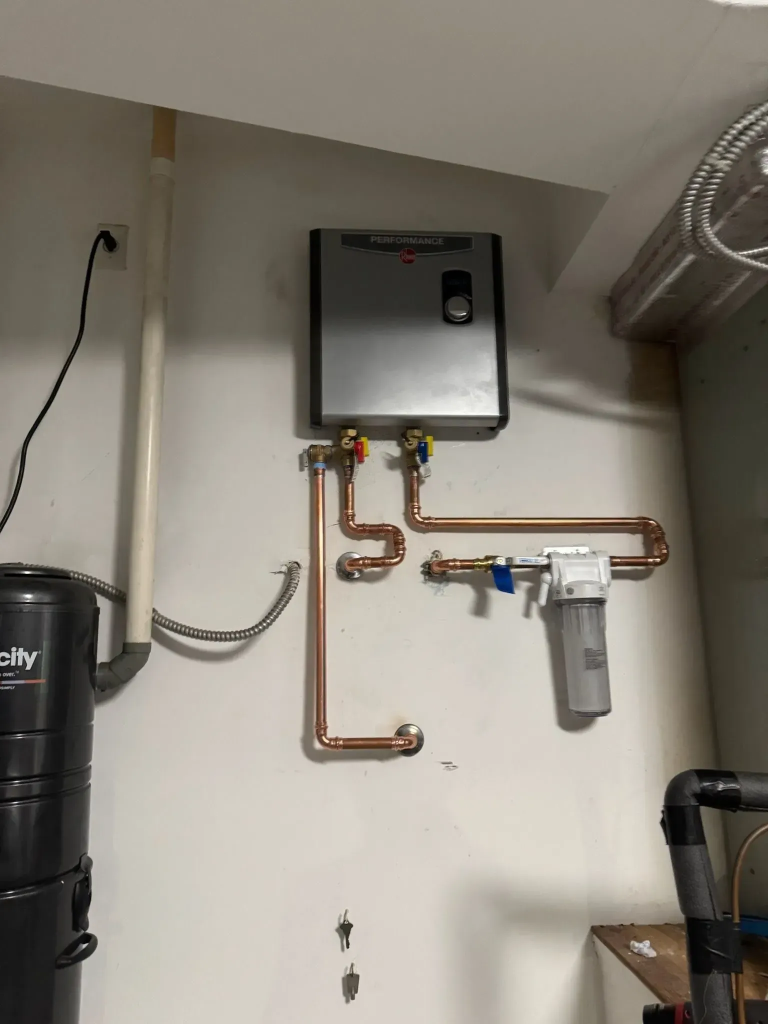 Wall-mounted tankless water heater with new copper piping and a whole-house water filter